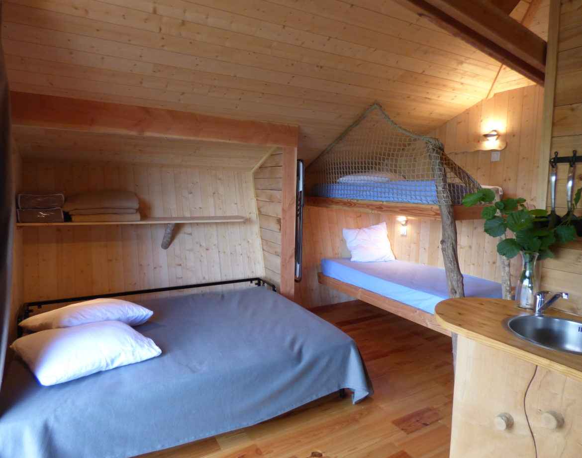 Chalet en bois cosy avec lit double et mezzanine, ambiance chaleureuse et naturelle.