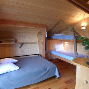 Chalet en bois cosy avec lit double et mezzanine, ambiance chaleureuse et naturelle.