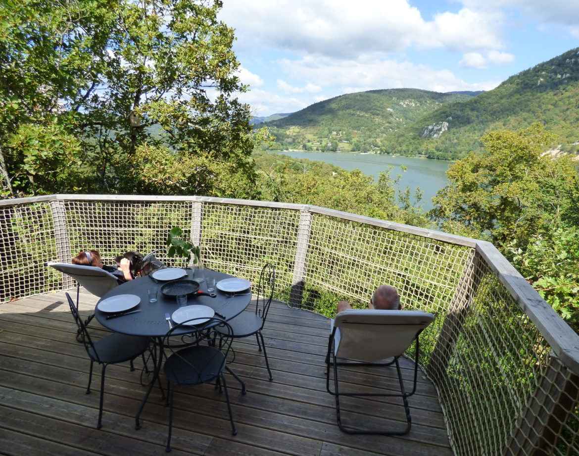 Cabane perchée avec vue panoramique sur le lac et la nature environnante.