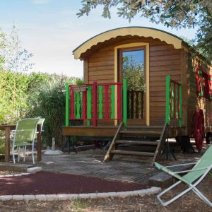 Roulotte colorée entourée de verdure, idéale pour un séjour insolite en Provence.