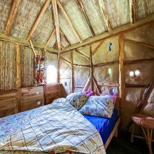 Chalet en bois au Grand-Est, intérieur chaleureux avec lit douillet et décor coloré.