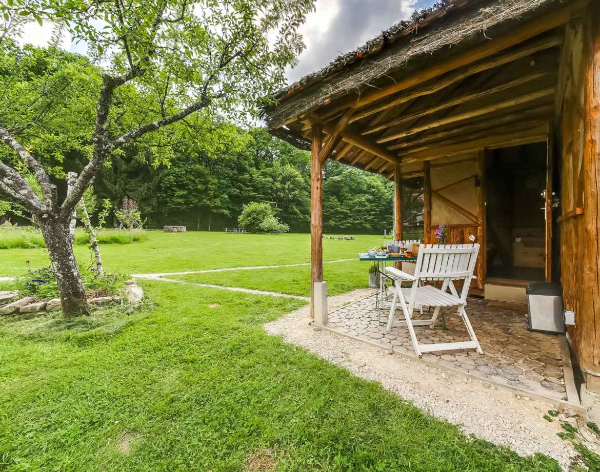 Cabane en bois à Grand-Est, avec terrasse et jardin verdoyant.