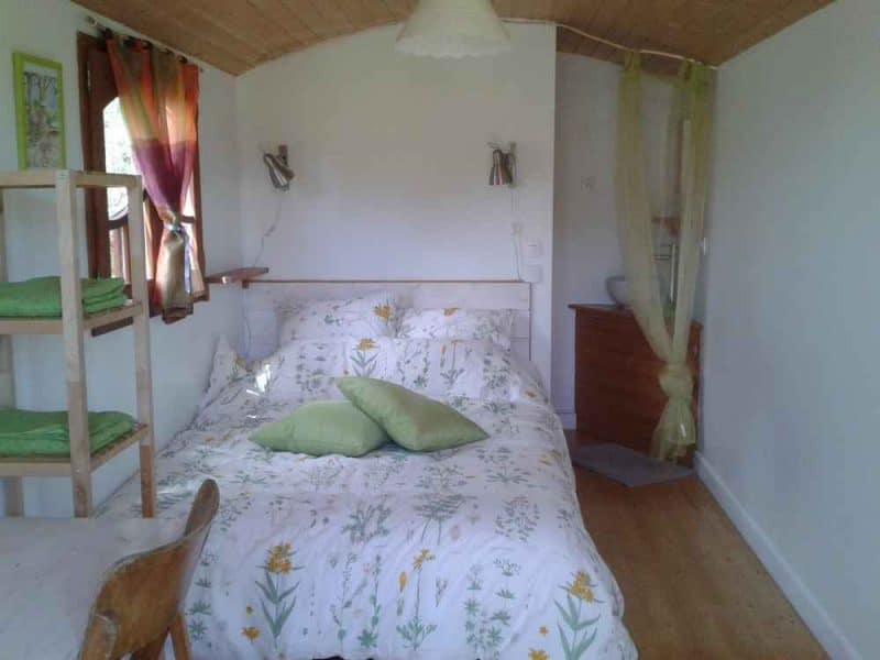 Chalet cosy avec lit double, décor floral et lumière naturelle apaisante.