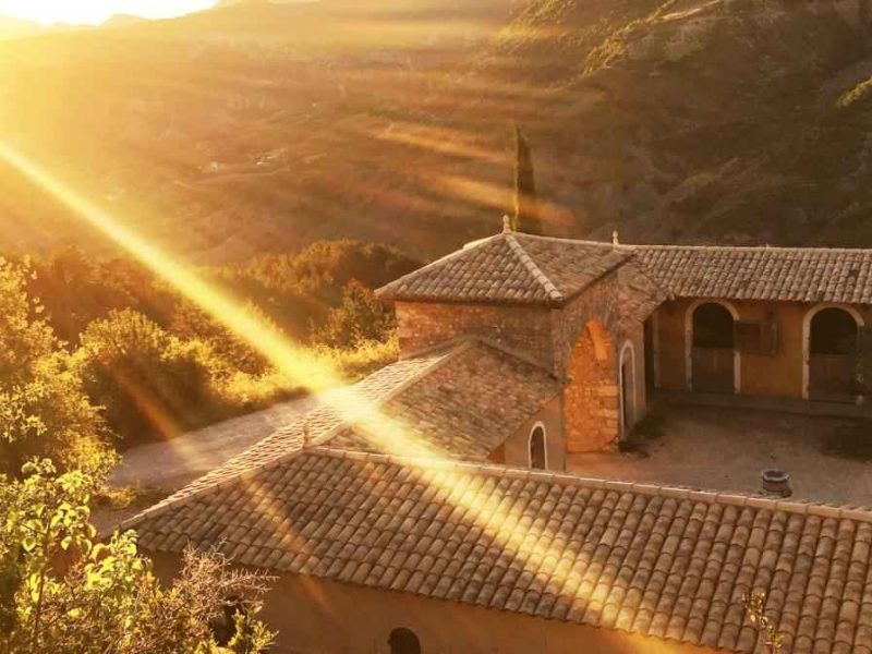 Maison dhôtes en pierre, baignée de lumière dorée au coucher du soleil.