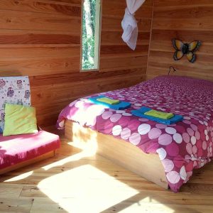 Chalet en bois coloré avec lit douillet et décorations murales charmantes.