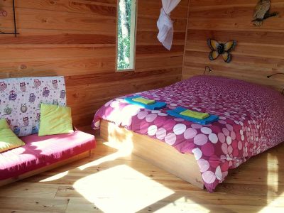 Chalet en bois coloré avec lit douillet et décorations murales charmantes.