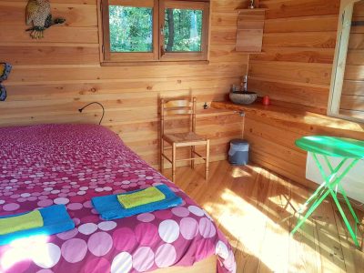 Chalet en bois avec lit douillet, décoré de couleurs vives et lumière naturelle.