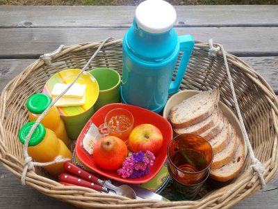Panier pique-nique coloré avec fruits, pain et boissons, parfait pour un hébergement insolite.