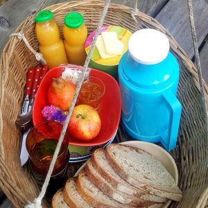 Panier de petit-déjeuner dans un hébergement insolite en Midi-Pyrénées, avec fruits et boissons.