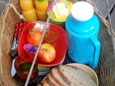 Panier de petit-déjeuner dans un hébergement insolite en Midi-Pyrénées, avec fruits et boissons.