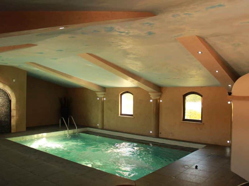 Gîte avec piscine intérieure, murs aux teintes douces et lumière naturelle.