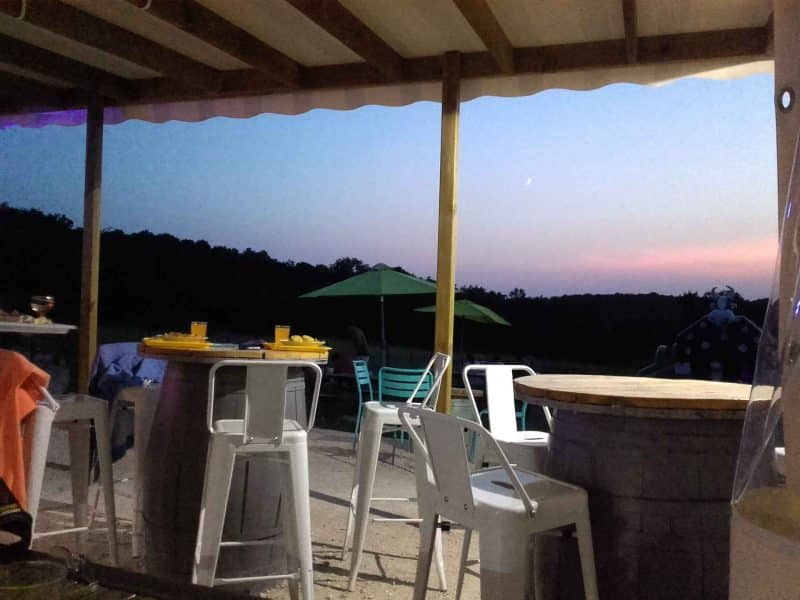 Terrasse dun gîte avec vue sur un coucher de soleil et des chaises colorées.