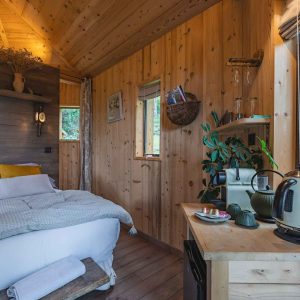 Cabane en bois cosy avec lit douillet et vue sur la nature en Auvergne-Rhône-Alpes.