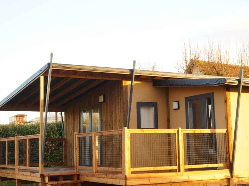 Cabane en bois avec terrasse, idéale pour un séjour en pleine nature.