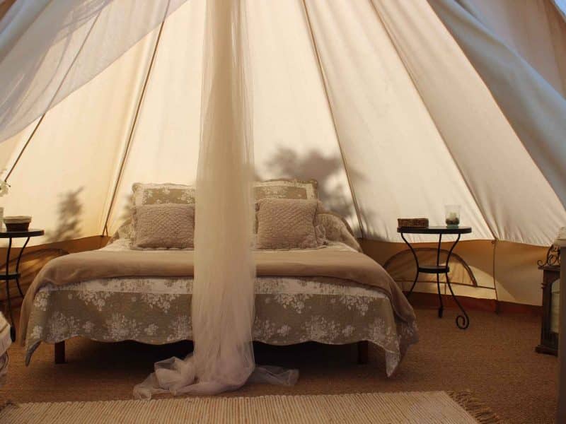 Tente de glamping en Auvergne-Rhône-Alpes, lit douillet avec décor naturel.