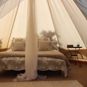 Tente de glamping en Auvergne-Rhône-Alpes, avec lit douillet et décoration élégante.