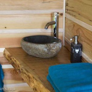 Élégante salle de bain en bois avec lavabo en pierre dans un hébergement insolite.