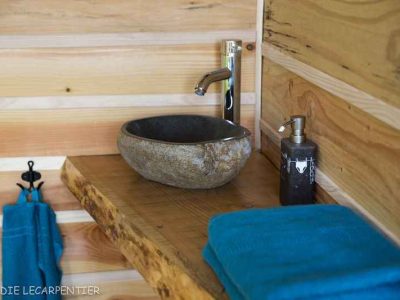 Élégante salle de bain en bois avec lavabo en pierre dans un hébergement insolite.