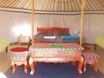 Yourte colorée avec un lit douillet et des meubles décoratifs en bois.