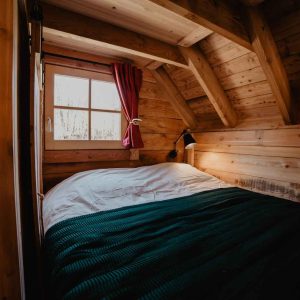 Chalet en bois cosy avec lit douillet et fenêtre lumineuse en Provence-Alpes-Côte dAzur.