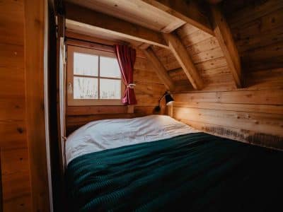 Chalet en bois cosy avec lit douillet et fenêtre lumineuse en Provence-Alpes-Côte dAzur.