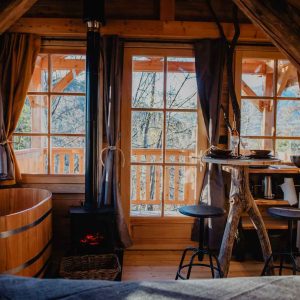 Cabane en bois avec baignoire en bois et vue sur la nature, idéale pour un séjour romantique.