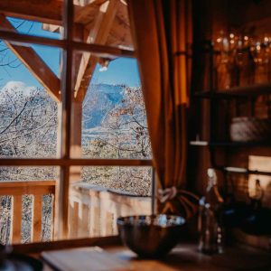 Cabane en bois avec vue panoramique sur les montagnes, ambiance chaleureuse et naturelle.