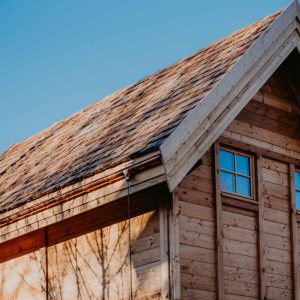Cabane en bois à la toiture en pente, nichée sous un ciel bleu azur.
