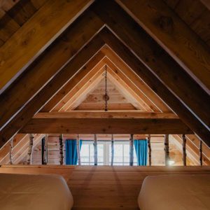 Cabane en bois avec vue sur des poutres apparentes et fenêtres lumineuses.