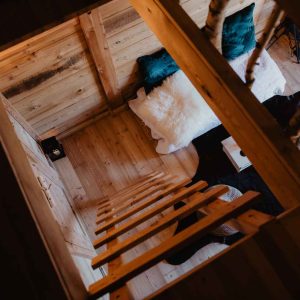 Cabane en bois avec échelle, vue sur un intérieur chaleureux et cosy.