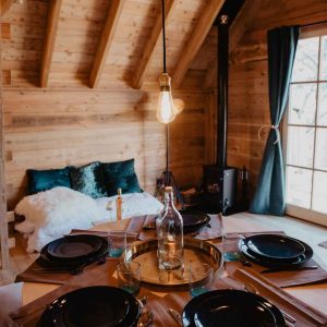 Cabane en bois chaleureuse avec table élégante et lumière suspendue.