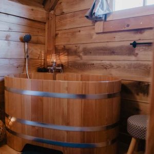 Hébergement insolite en bois avec baignoire en bois et ambiance chaleureuse.