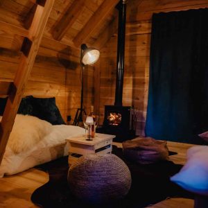 Cabane en bois chaleureuse avec poêle à bois et ambiance cosy.