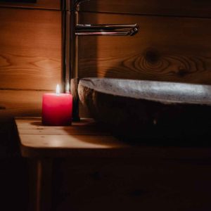 Élégante salle de bain en bois avec un lavabo en pierre et une bougie rouge.
