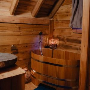 Hébergement insolite en bois avec baignoire en bois et ambiance chaleureuse.