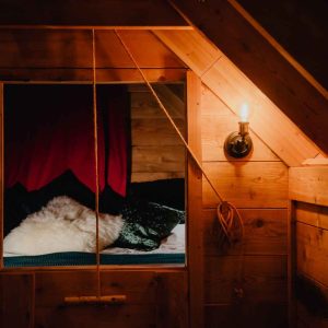 Cabane en bois avec une vue sur un lit douillet et des lumières chaleureuses.