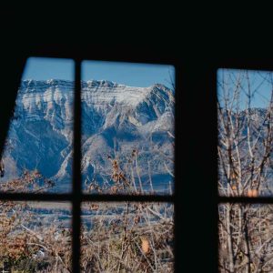Vue depuis un chalet en bois, avec des montagnes majestueuses en arrière-plan.