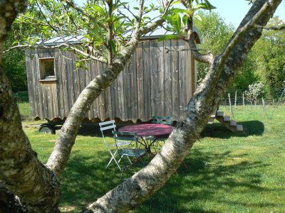Hébergement insolite en Limousin : une roulotte en bois avec une table en extérieur.