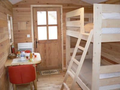 Cabane en bois à Limousin, avec lits superposés et une table conviviale.