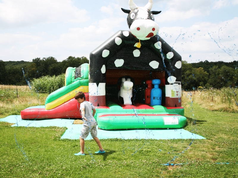 Hébergement touristique : aire de jeux gonflable en forme de vache, avec toboggan coloré.