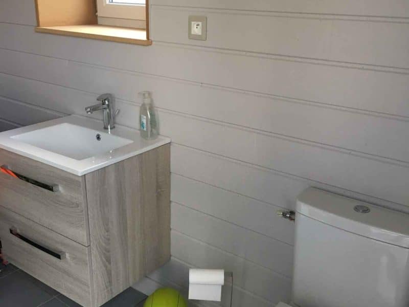 Salle de bain moderne dans un hébergement touristique, avec meuble en bois et accessoires colorés.