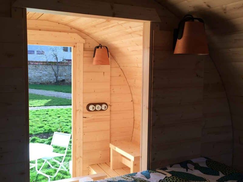 Cabane en bois avec vue sur un jardin verdoyant et une décoration intérieure chaleureuse.