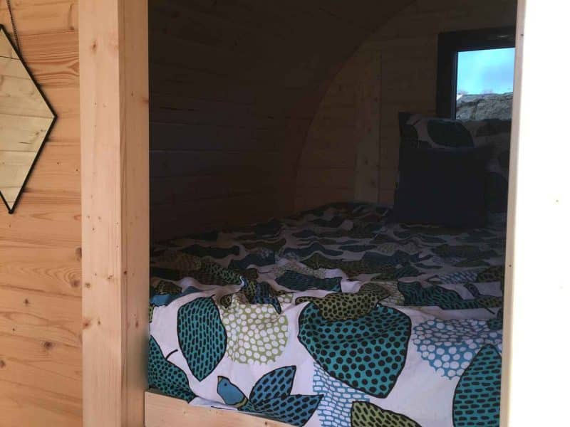 Cabane en bois avec lit douillet et décoration colorée, ambiance chaleureuse.
