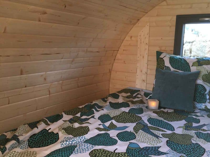 Cabane en bois avec lit douillet, décorée de motifs de feuilles colorées.