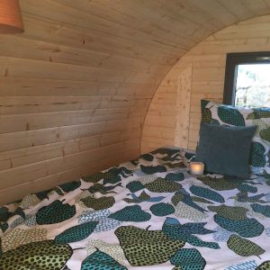 Hébergement insolite en Bourgogne : intérieur en bois avec un lit décoré de motifs colorés.