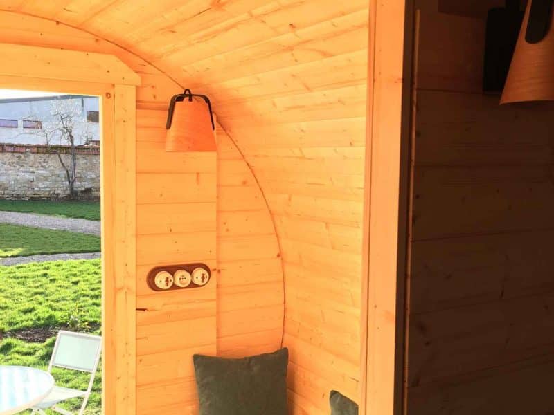 Intérieur dune cabane en bois, lumineux avec banc et coussins confortables.