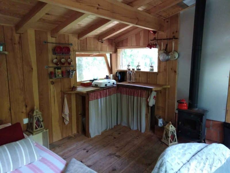 Cabane en bois chaleureuse avec cuisine équipée et fenêtres lumineuses.