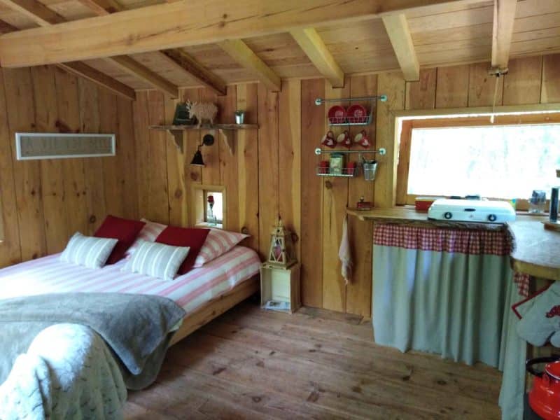 Chalet en bois chaleureux avec lit douillet et cuisine rustique.