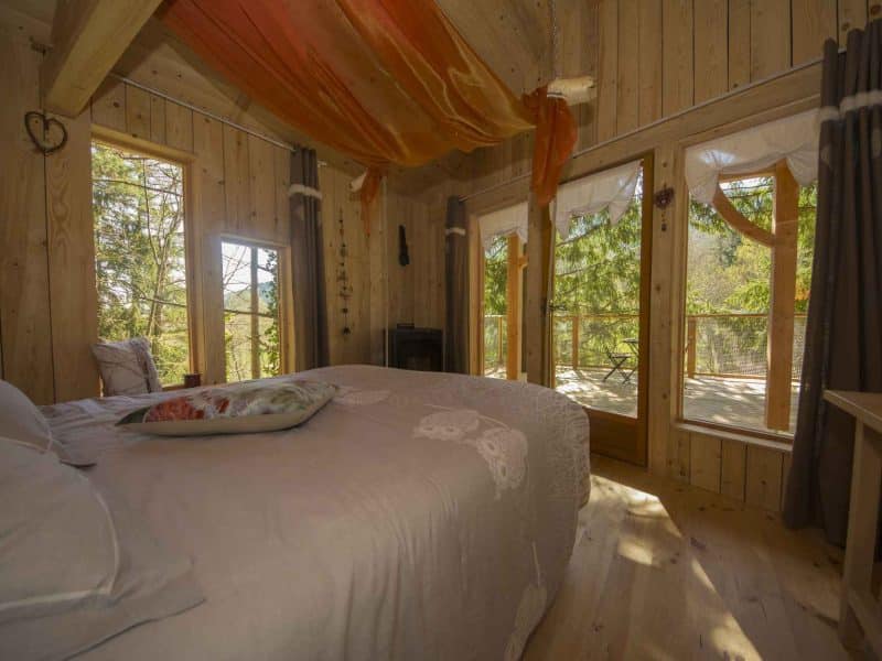 Chalet en bois avec une vue sur la nature, décoré de drapés colorés.