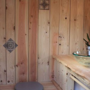 Hébergement insolite en bois en Auvergne-Rhône-Alpes, avec lavabo en verre et orchidée.